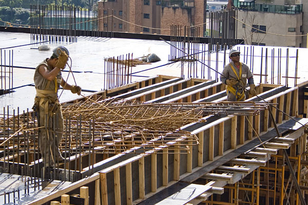 dois trabalhadores da construção civil executando uma estrutura metálica em um prédio em construção